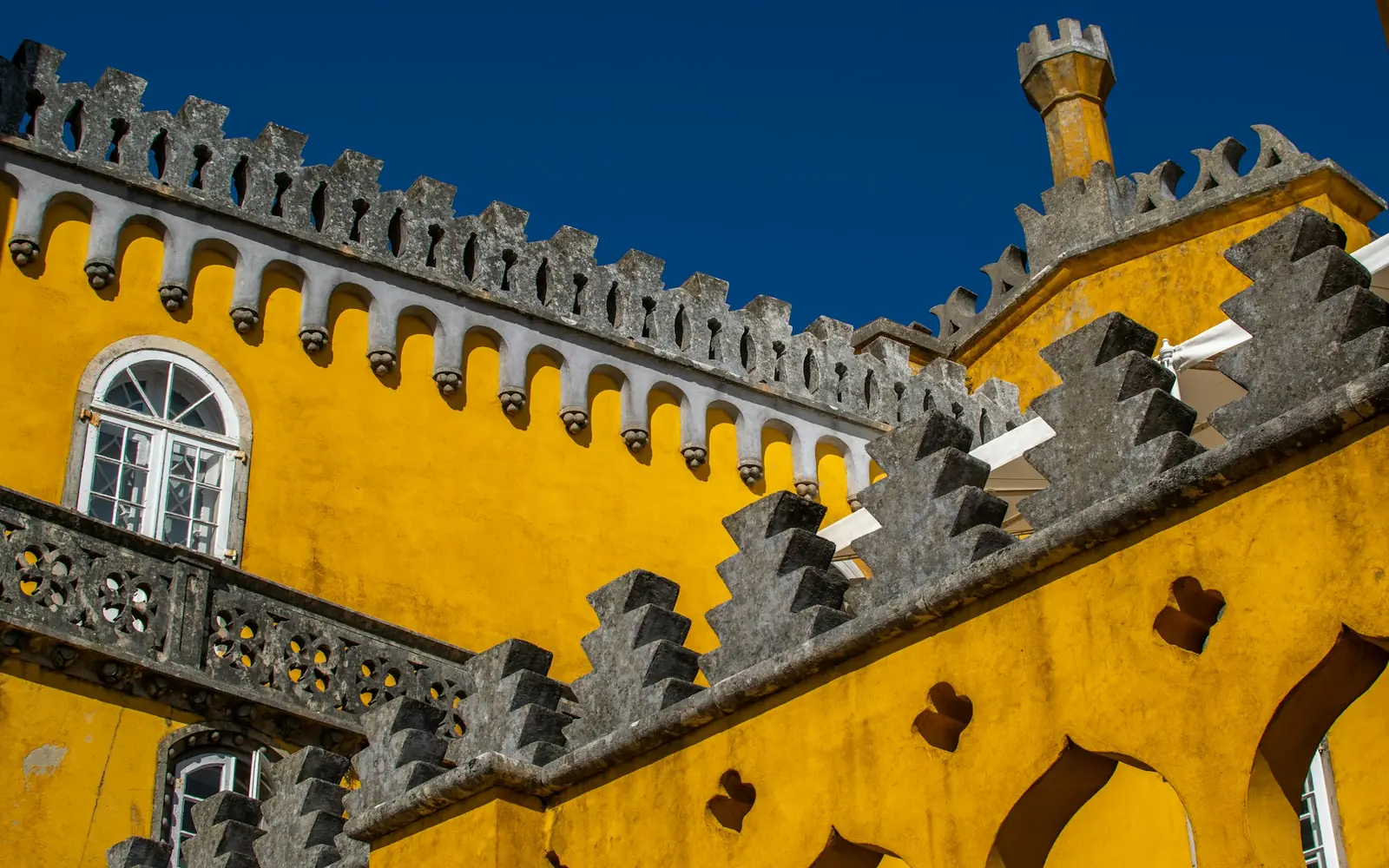 Yellow crenellated walls of Pena Palace lit by strong sun
