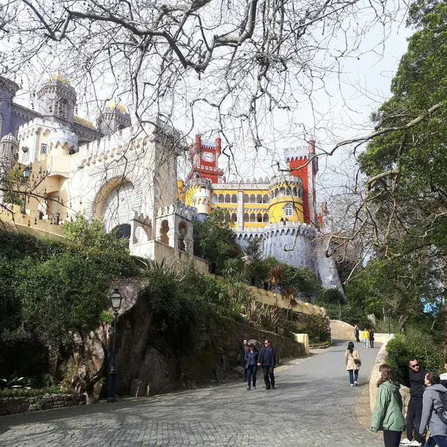 Visitors walking the cobbled path through the Pena park towards the palace