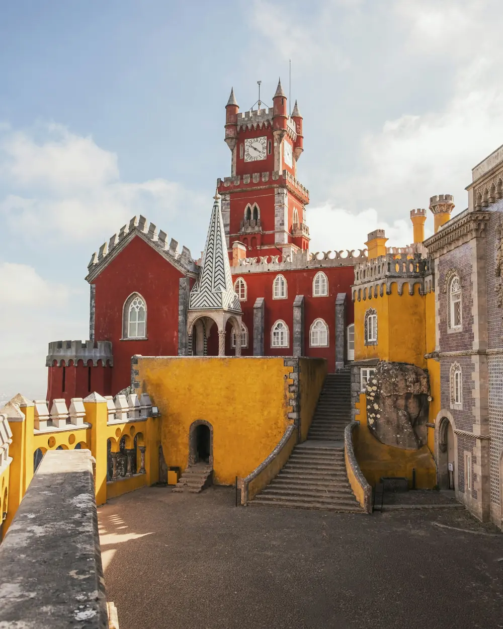 The red clock tower of Pena Palace rising above the yellow stair